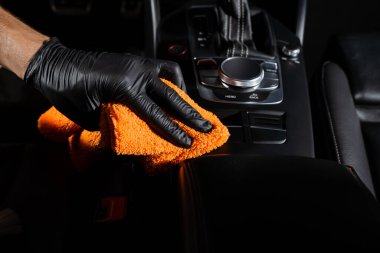 Otomobil servisinde mikrofiber kullanarak vites kutusunun ve gösterge panelinin el arabasıyla kurulanması. Temizlikçi, kuru araba.