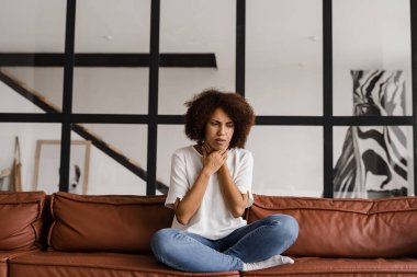 Gırtlak iltihabı ilk belirtileri boğaz ağrısı. Hasta Afrikalı Amerikalı kız acıdan boğazına dokunuyor. Mevsimsel hastalık ilacı