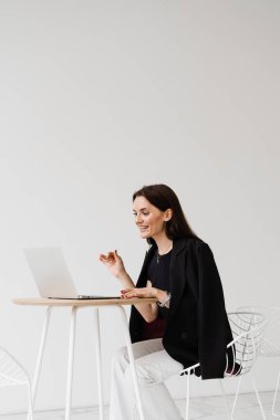 Dizüstü bilgisayarı olan kız menajer, beyaz ofiste trendleri ve görevleri tartışıyor. İş arkadaşları ve iş ortaklarıyla çevrimiçi video toplantısı. Takım tartışması ve problem çözümü