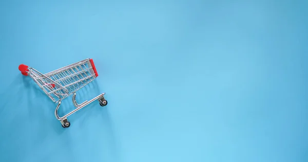 empty shopping cart on blue background, top view
