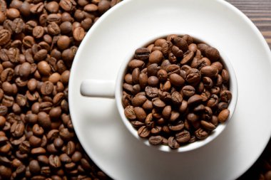 Kahve çekirdekleri ile dolu beyaz kahve fincanı.