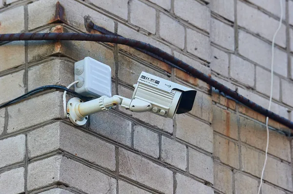 Une caméra de surveillance est accrochée à un mur de briques — Photo