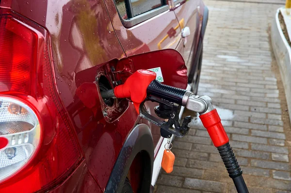 Die rote Pistole wird in den Gastank eines roten PKW zum Betanken mit Benzin gesteckt — Stockfoto