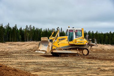 A yellow tractor bulldozer stands in a sand pit