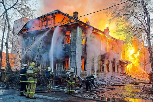 Bombeiros extinguem um incêndio em uma casa de madeira de dois andares — Fotografia de Stock