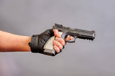 Adamın biri elinde gri bir arka planda siyah bir tabanca tutuyor. Yüksek kalite fotoğraf