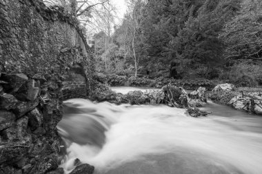 Lond exposure of the river Avill flowing under Lovers bridge in the grounds of Dunster castle in Somerset