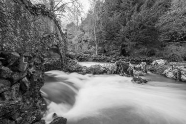 Lond exposure of the river Avill flowing under Lovers bridge in the grounds of Dunster castle in Somerset