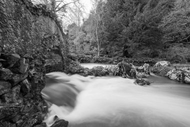 Lond exposure of the river Avill flowing under Lovers bridge in the grounds of Dunster castle in Somerset
