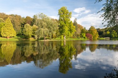 Wiltshire 'daki Stourhead bahçesindeki gölün etrafındaki sonbahar renklerinin görüntüsü
