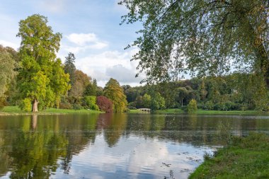 Wiltshire 'daki Stourhead bahçesindeki gölün etrafındaki sonbahar renklerinin görüntüsü