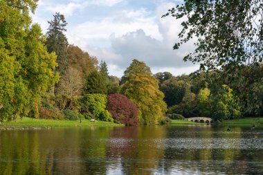 Wiltshire 'daki Stourhead bahçesindeki gölün etrafındaki sonbahar renklerinin görüntüsü