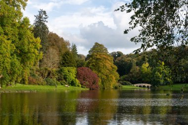 Wiltshire 'daki Stourhead bahçesindeki gölün etrafındaki sonbahar renklerinin görüntüsü