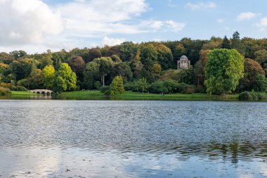 Wiltshire 'daki Stourhead bahçesindeki gölün etrafındaki sonbahar renklerinin görüntüsü