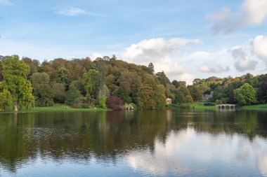 Wiltshire 'daki Stourhead bahçesindeki gölün etrafındaki sonbahar renklerinin görüntüsü