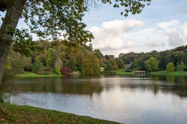 Wiltshire 'daki Stourhead bahçesindeki gölün etrafındaki sonbahar renklerinin görüntüsü