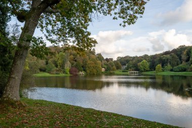 Wiltshire 'daki Stourhead bahçesindeki gölün etrafındaki sonbahar renklerinin görüntüsü