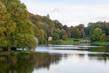 Wiltshire 'daki Stourhead bahçesindeki gölün etrafındaki sonbahar renklerinin görüntüsü