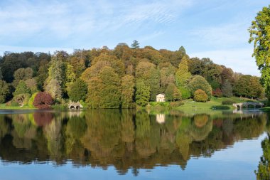 Wiltshire 'daki Stourhead bahçesindeki gölün etrafındaki sonbahar renklerinin görüntüsü
