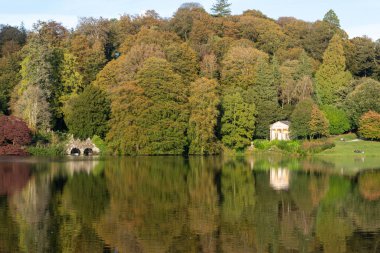 Wiltshire 'daki Stourhead bahçesindeki gölün etrafındaki sonbahar renklerinin görüntüsü