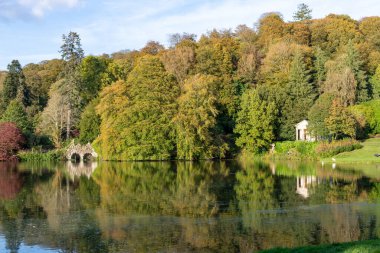 Wiltshire 'daki Stourhead bahçesindeki gölün etrafındaki sonbahar renklerinin görüntüsü