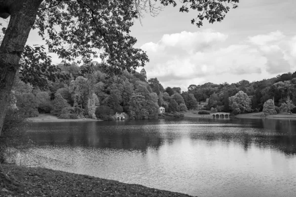 Stourhead 'deki gölün ve Wiltshire' daki bahçelerin siyah beyaz fotoğrafı.