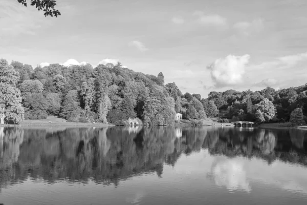 Stourhead 'deki gölün ve Wiltshire' daki bahçelerin siyah beyaz fotoğrafı.