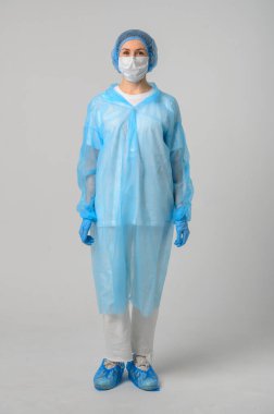 Doktor ya da hemşire tıbbi önlük, maske ve koruyucu eldiven giyer.