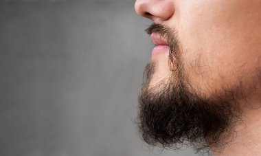 Gri arka planda genç adamın sakalı ve bıyığı, fotokopi alanıyla yakın plan.