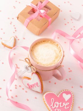Idyllic Sevgililer Günü sabahı, el yapımı hediye, latte ve beyaz arka planda aşk mesajı olan kurabiyeler.