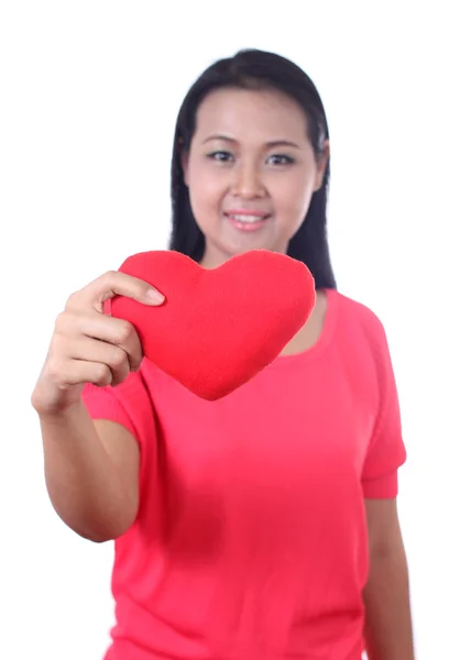 Mujer joven sosteniendo una almohada roja en forma de corazón, aislada en blanco — Foto de Stock