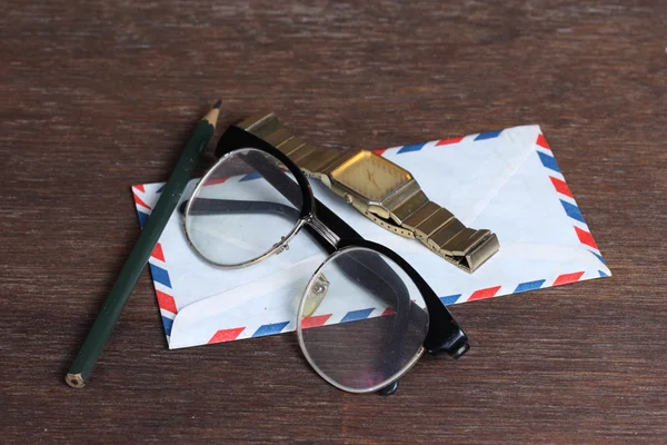 Groupe d'objets sur bureau en bois. Lunettes, montre, enveloppe et pe — Photo