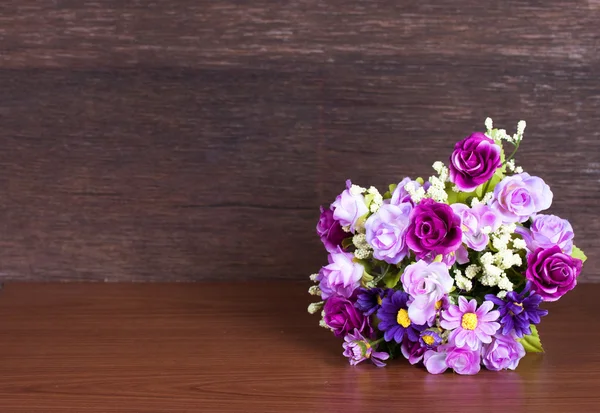 Bunte künstliche Blume auf Holz Hintergrund — Stockfoto
