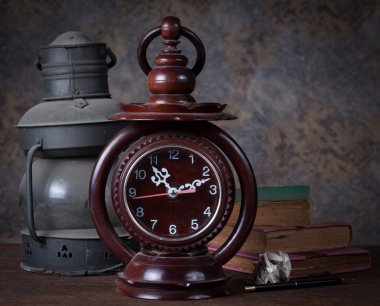 Eski saat, eski paslı gaz lambası, eski kitaplar, kurşun kalem