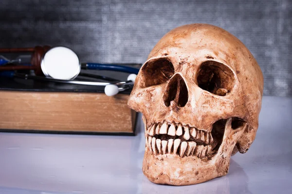 Verweerde menselijke schedel en stethoscoop — Stockfoto