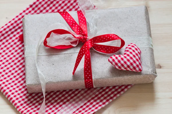 Homemade red heart and gift with red ribbon — Stock Photo, Image