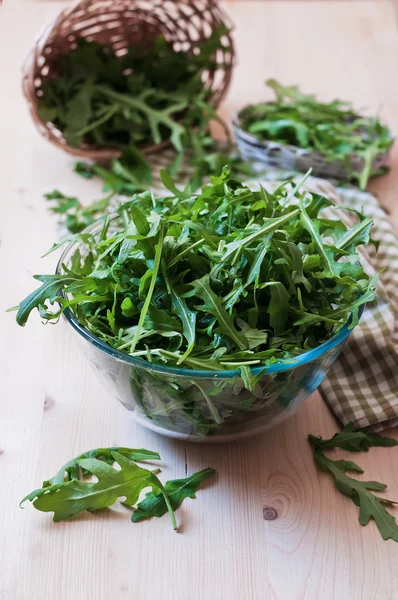 Arugula proaspătă într-o placă de sticlă pe masa de lemn — Fotografie, imagine de stoc