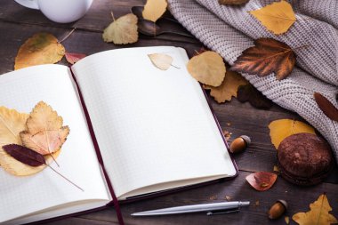 Sonbahar sezonu konsepti, güzel sonbahar kompozisyonu defter, çay, sonbahar yaprakları, kırsal ahşap masa üzerinde çikolatalı badem kurabiyesi.