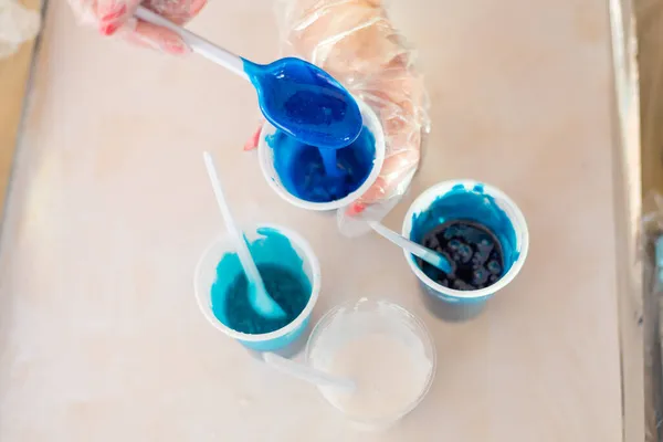 Résine époxy de différentes couleurs bleues dans une tasse pour couler du bois stabilisant, art abstrait. Processus de fabrication d'accessoires à partir de résine.Mélange coloré de résine chimique dans une tasse en plastique — Photo