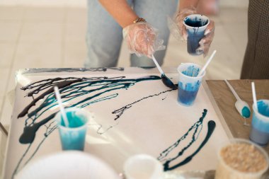 Epoksi reçine, soyut sanat için farklı mavi renkte. Kadın ellerinin reçineden aksesuar yapma süreci. Plastik bardakta renkli reçine kimyasalı karıştırmak.