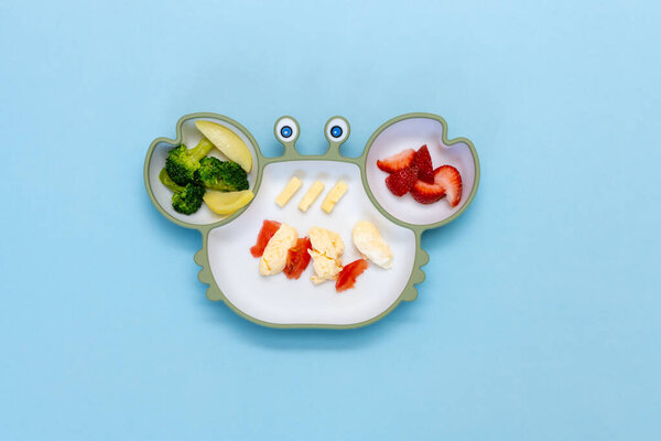 Baby Led weaning, blw. First toddler food. Soft eco plastic tableware with mixed vegetable. Healthy nutrition for kid, self feeding. Top view of silicone plate with spoon finger food for kid.