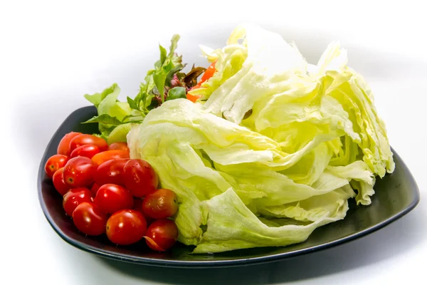 Färska grönsaker sallad på svart plåt — Stockfoto