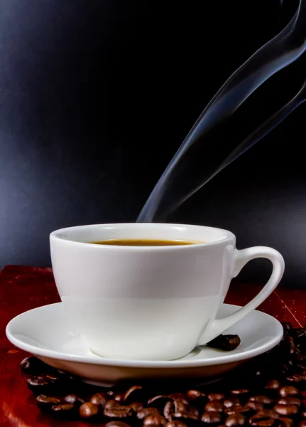 Tasse Kaffee mit Kaffeebohnen auf schwarzem Hintergrund. — Stockfoto