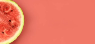 Pembe arka planda, yarım taze karpuz. Yakın plan, yatay afiş. Metin için alanı kopyala