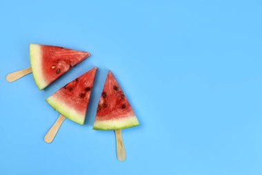 Mavi arka planda bir çubukta karpuz buzlu dondurma.