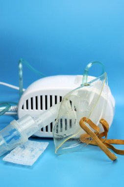 Mavi arka planda maske olan nebulizör spreyi. Seçici odak