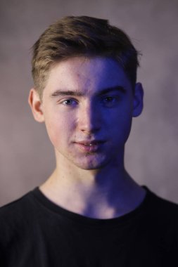 Gri arka planda yakışıklı bir gencin portresi. Dikey yönelim