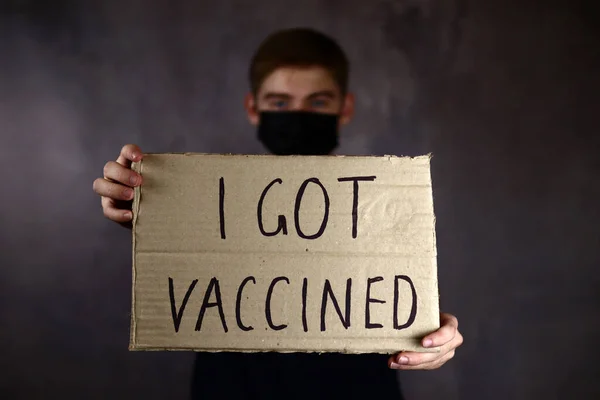私が予防接種を受けたポスターを手にした青年は 防護医療用マスクの中で コロナウイルスのパンデミックと戦うという概念を — ストック写真