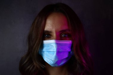 Koronavirüs hastalığına karşı koruyucu maske takan genç bir kadın.