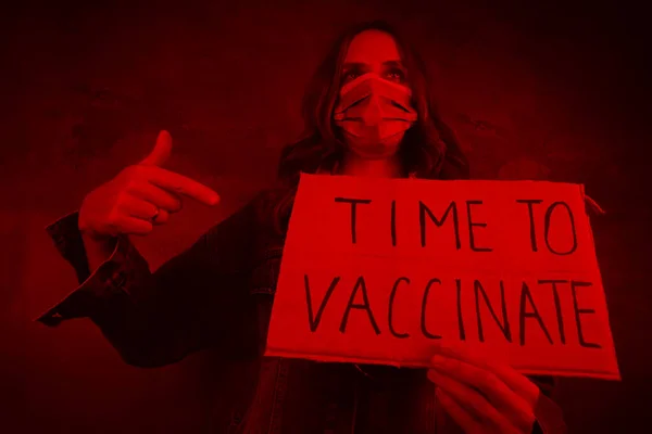 ポスターを予防接種する時間のある医療マスクの若い女性 悲劇的な赤の着色 — ストック写真